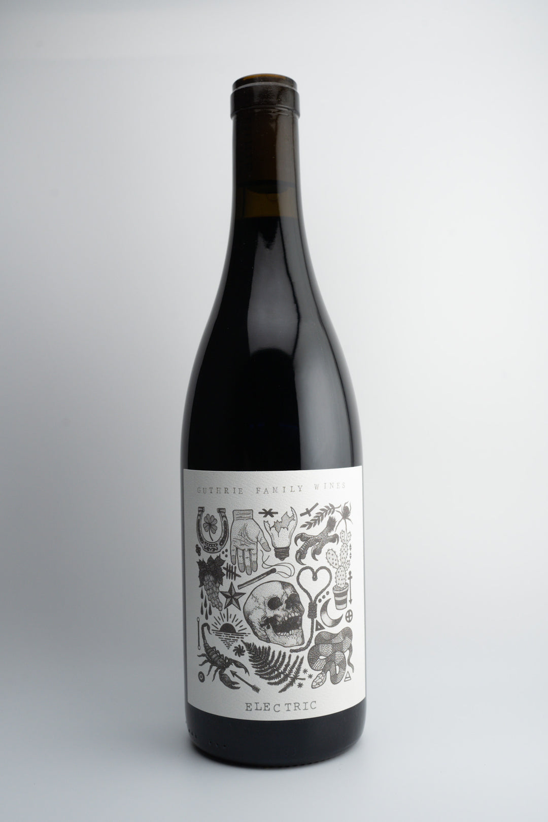 A bottle of 2019 Guthrie Family Wines 'Electric' Syrah with a dark label featuring skull and bone illustrations.