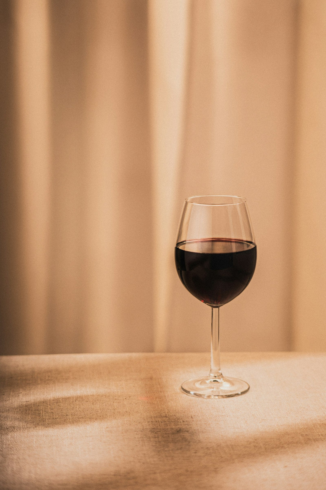 A single glass of red wine on a wooden table