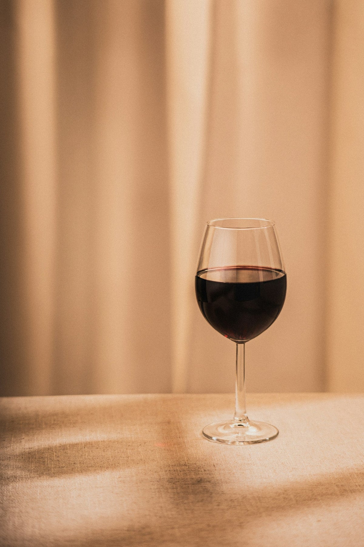 A single glass of red wine on a wooden table