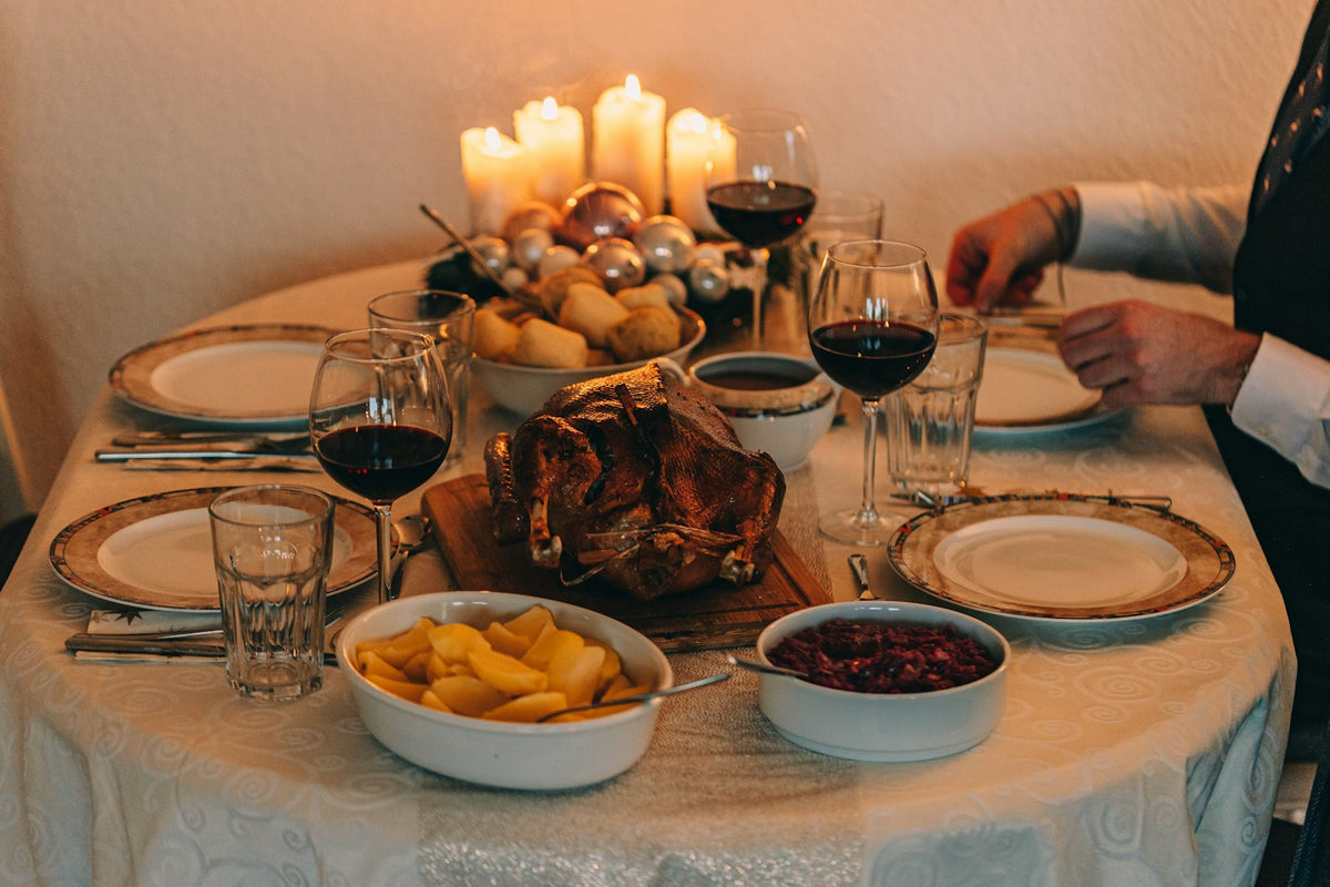 Thanksgiving dinner table with roast turkey, sides and glasses of red wine by candlelight