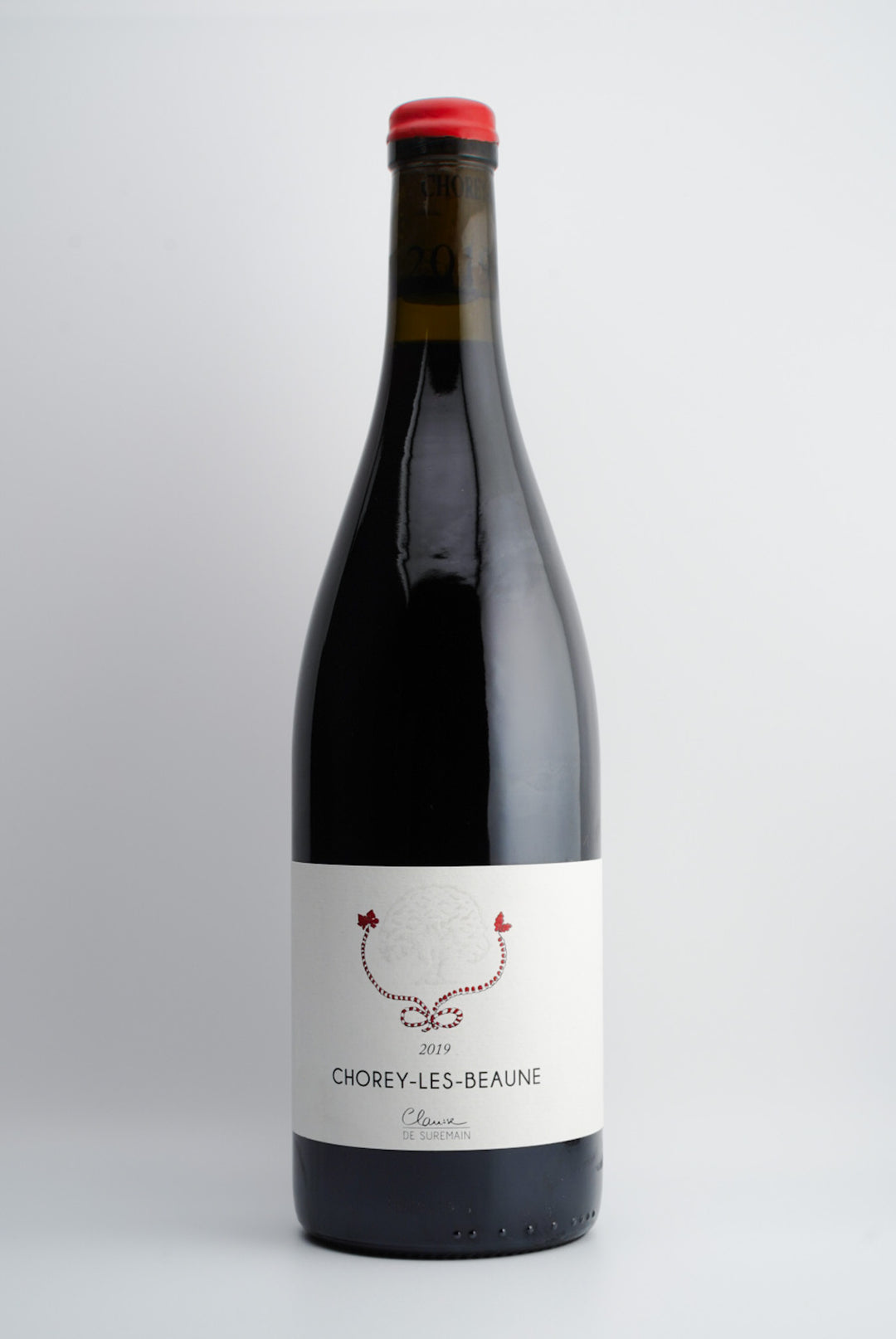 A bottle of 2019 Clarisse de Suremain Chorey-Les-Beaune Rouge wine with a red cap and a label featuring the wine variety and region.