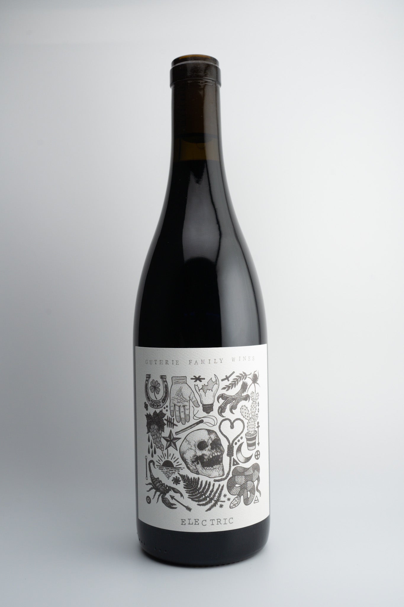 A bottle of 2019 Guthrie Family Wines 'Electric' Syrah with a dark label featuring skull and bone illustrations.