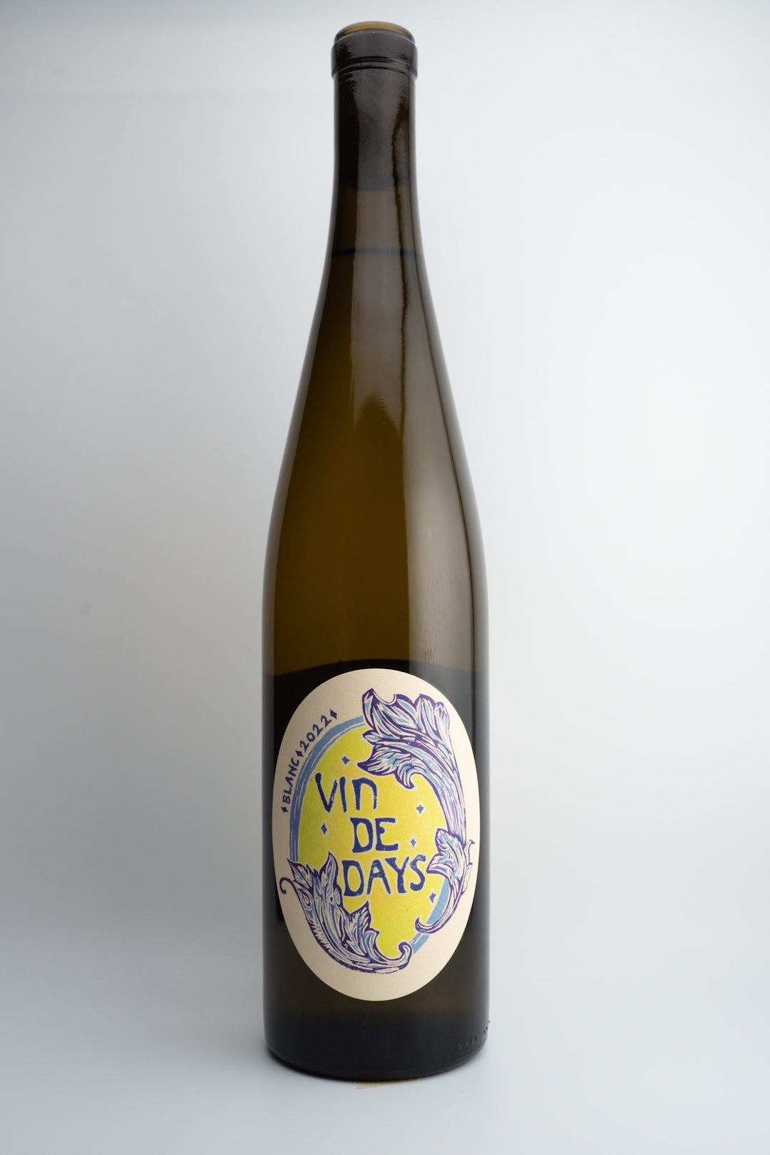A bottle of 2022 Days Wines 'Vin de Days Blanc' with a label that has purple and yellow design elements, indicating it is an organic wine from the Willamette Valley, Oregon.