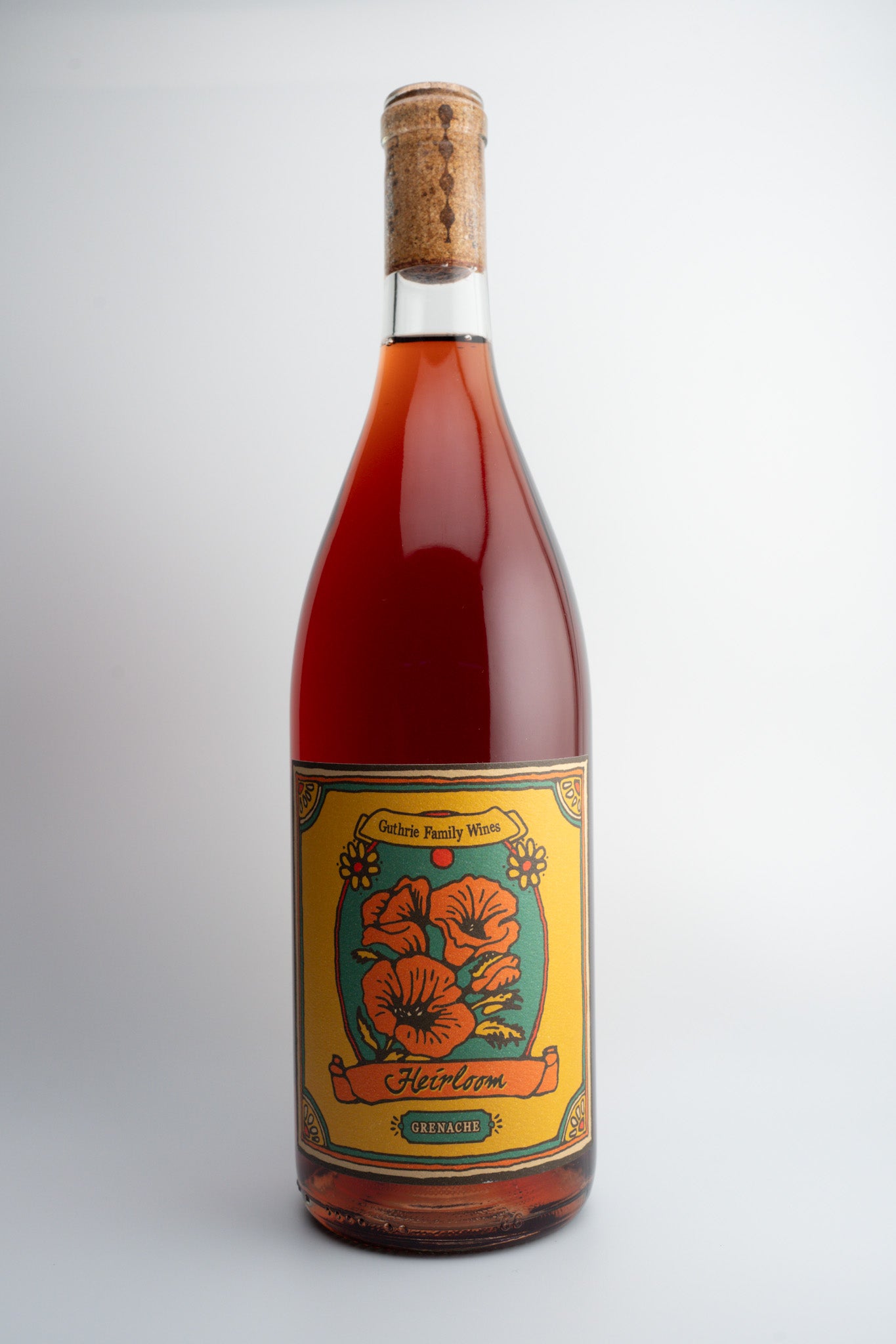 A bottle of 2022 Guthrie Family Wines "Heirloom" Carbonic Grenache with a label featuring floral graphics and text, indicating the variety and vintage.