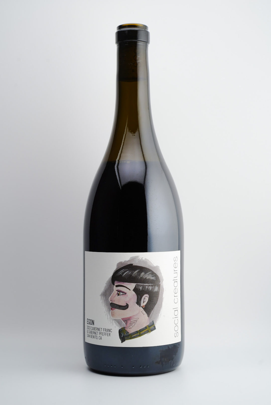 A bottle of 2023 Social Creatures 'Egon' Cabernet Franc/Cabernet Pfeffer wine with a label featuring a stylized illustration of a person's face.