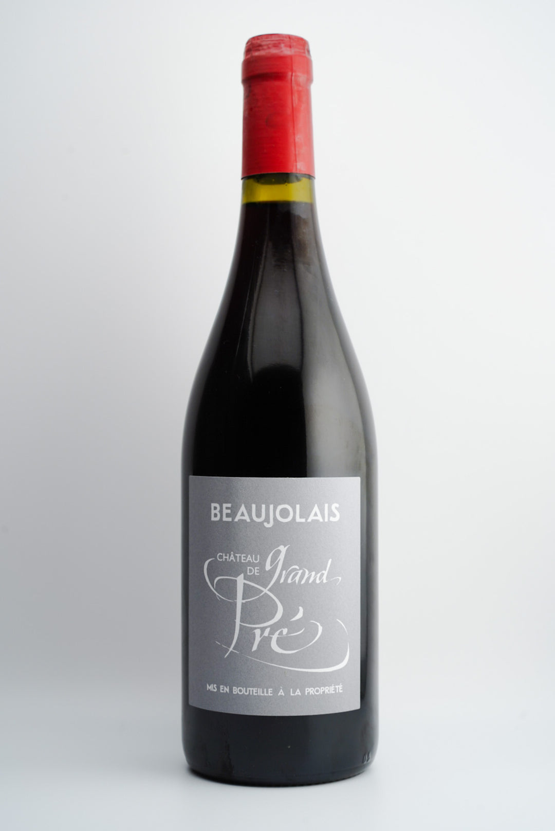 A bottle of Chateau Grand Pré, Beaujolais Villages, France 2021 red wine with a white label and a red cap.