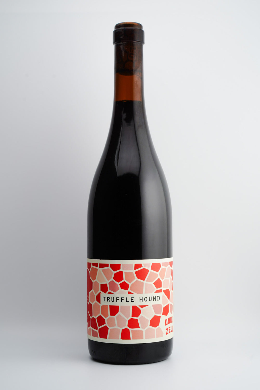 A bottle of Unico Zelo Truffle Hound Red Blend wine with a label featuring a geometric pattern in red and white on a dark background.
