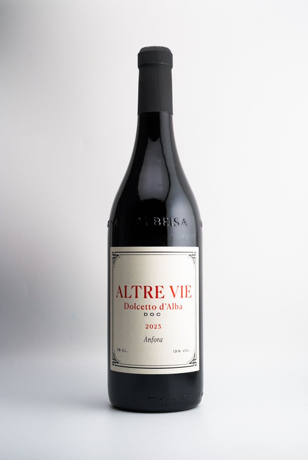 A bottle of Altre Vie 'Anfora' Dolcetto d’Alba DOC, Piedmont, Italy 2023 wine with a white label, red and black text, and a visible wine rack background.